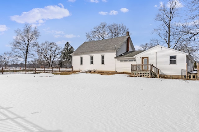 snow covered rear of property featuring a chimney