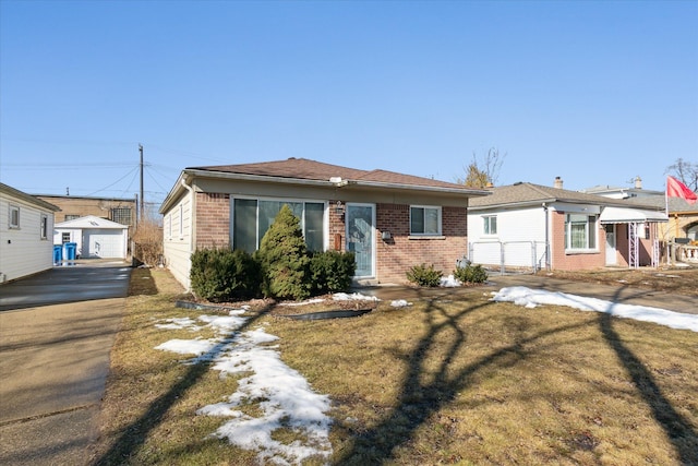 view of front of house featuring a front lawn, an outbuilding, concrete driveway, and brick siding