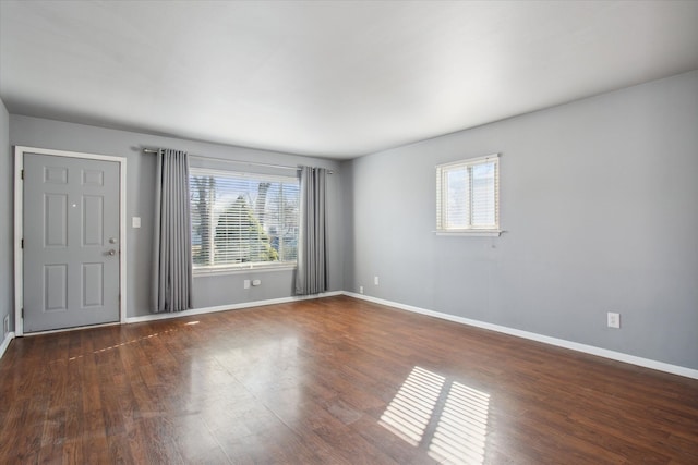 spare room with baseboards and dark wood-style flooring