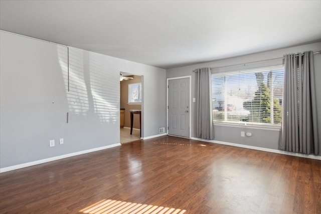 spare room with dark wood-style floors, visible vents, baseboards, and a ceiling fan