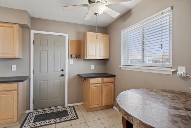 kitchen featuring light tile patterned floors, light brown cabinetry, dark countertops, and a ceiling fan