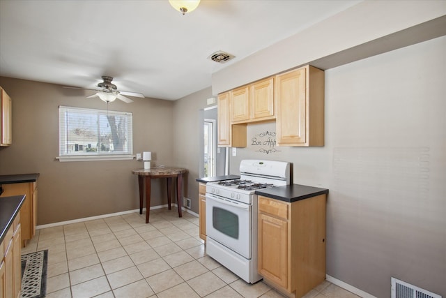 kitchen featuring dark countertops, white gas range oven, visible vents, and baseboards