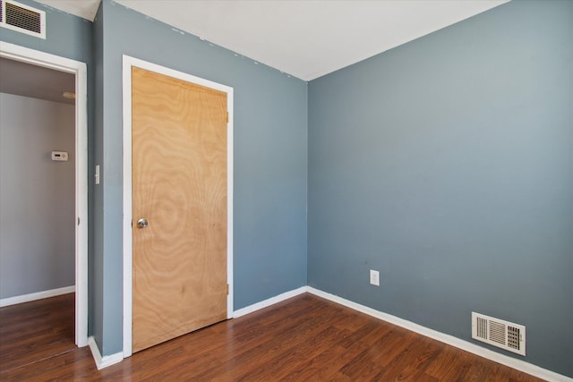 spare room with baseboards, visible vents, and dark wood-type flooring