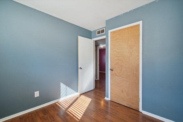 unfurnished bedroom featuring dark wood-style floors, visible vents, and baseboards