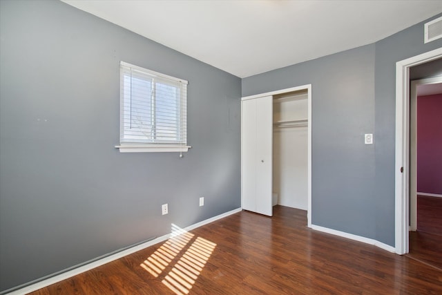 unfurnished bedroom with visible vents, a closet, baseboards, and dark wood-style flooring