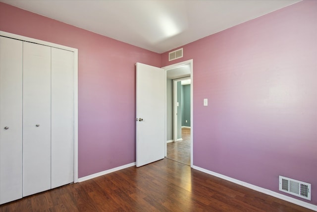 unfurnished bedroom featuring baseboards, visible vents, dark wood finished floors, and a closet