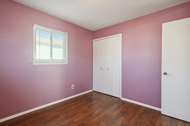 unfurnished bedroom featuring dark wood-style floors, a closet, and baseboards