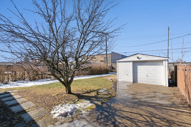 yard layered in snow with a garage, driveway, and an outdoor structure