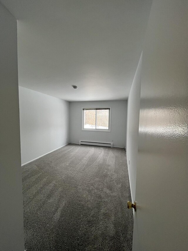 carpeted empty room with a baseboard heating unit and baseboards