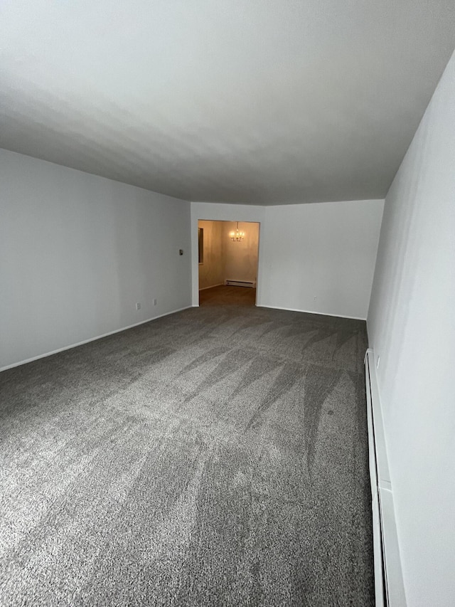 carpeted empty room featuring a baseboard radiator, a notable chandelier, and baseboard heating