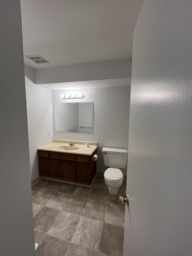 bathroom featuring visible vents, toilet, vanity, and baseboards