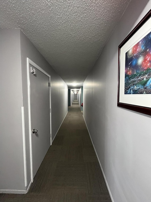 corridor featuring baseboards and a textured ceiling