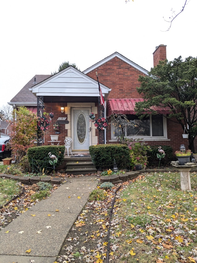 bungalow-style house with brick siding and a chimney