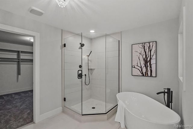 full bath with a stall shower, a freestanding bath, a spacious closet, and baseboards