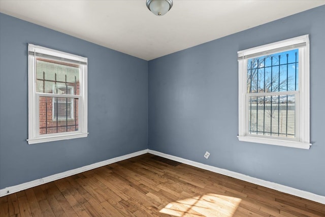 empty room featuring visible vents, baseboards, and hardwood / wood-style floors