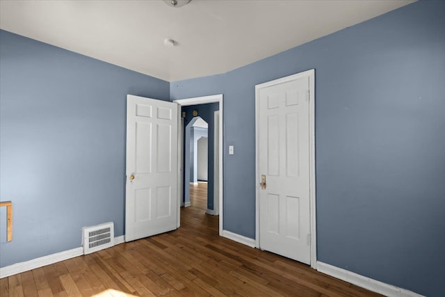 unfurnished bedroom with dark wood-style floors, visible vents, and baseboards