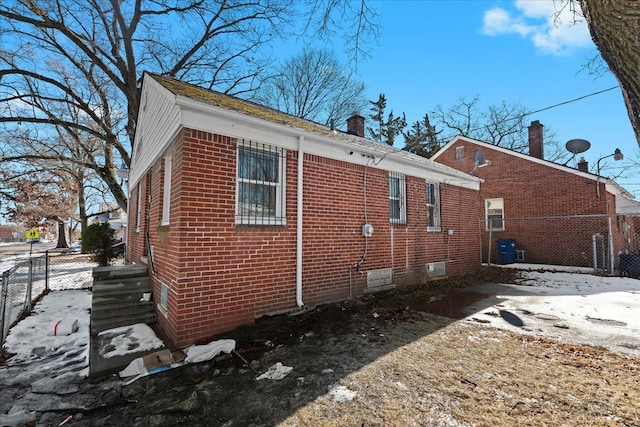 view of side of home with brick siding, crawl space, and fence