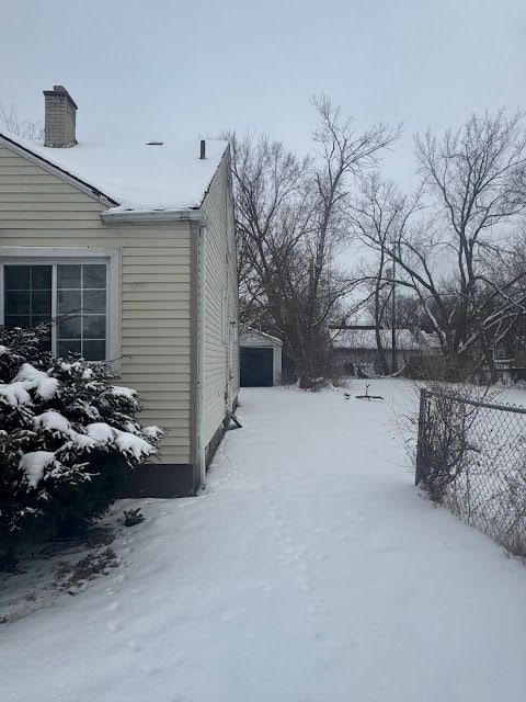 snowy yard with fence and a detached garage