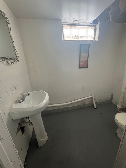 half bathroom featuring concrete flooring and toilet