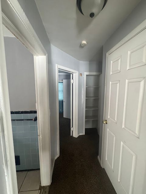 hallway with wainscoting and tile walls