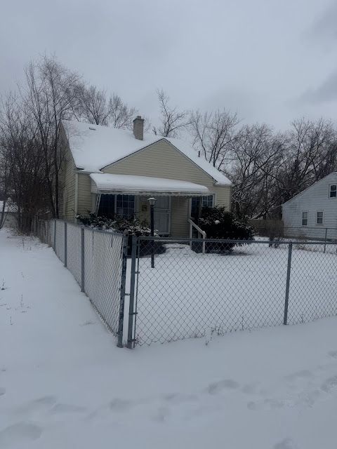 snow covered property with a fenced front yard