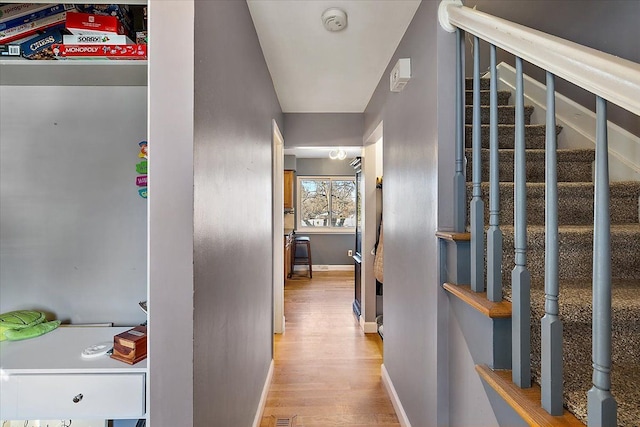 hall featuring baseboards, stairs, and light wood-style floors