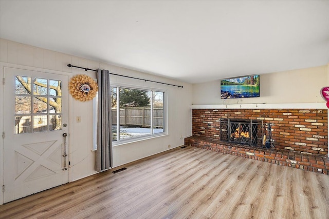 unfurnished living room with light wood finished floors, a fireplace, and visible vents