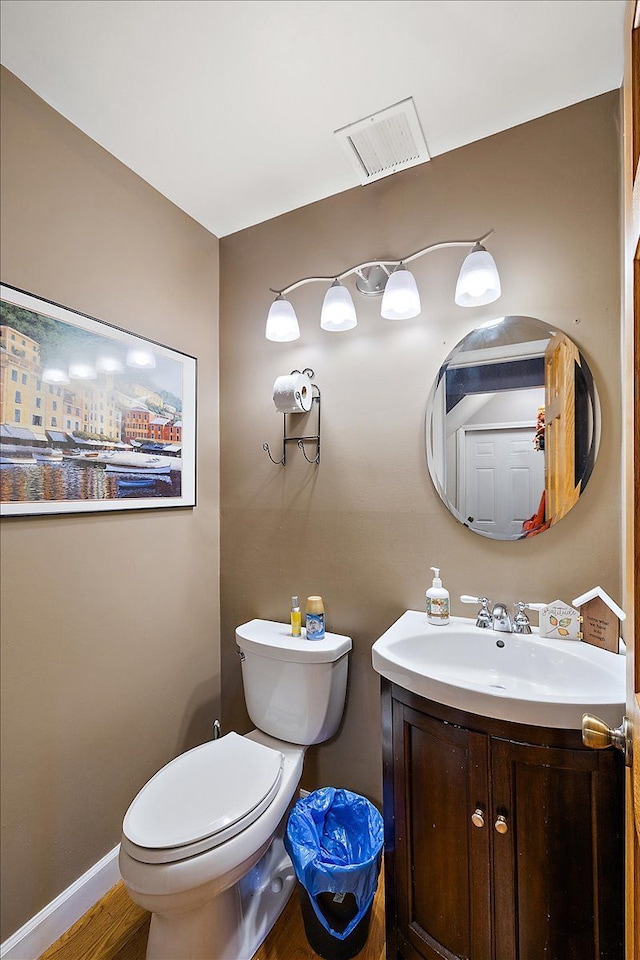 bathroom featuring toilet, wood finished floors, vanity, visible vents, and baseboards