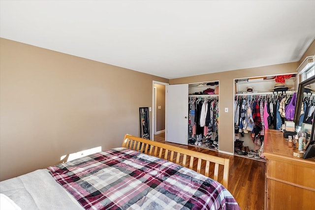 bedroom with wood finished floors and two closets