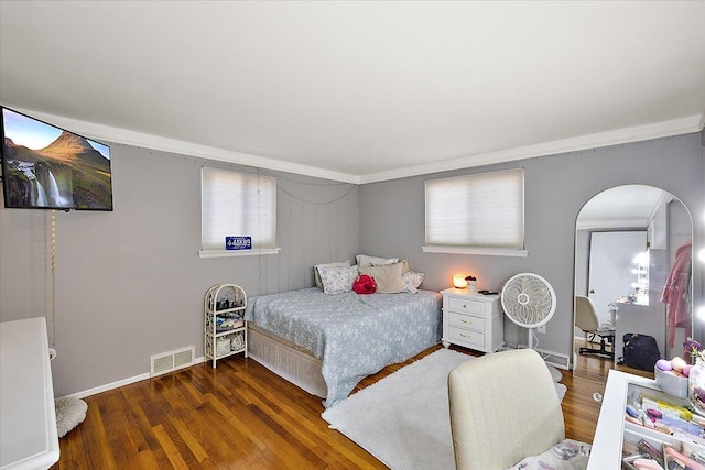 bedroom featuring dark wood-style floors, arched walkways, visible vents, and baseboards