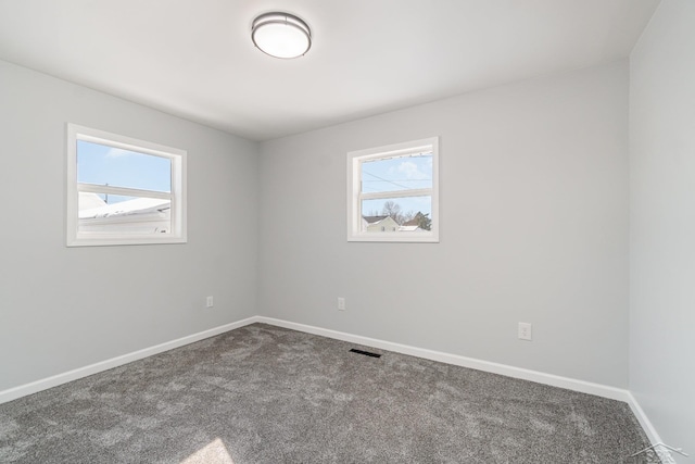 empty room featuring baseboards, carpet flooring, visible vents, and a healthy amount of sunlight