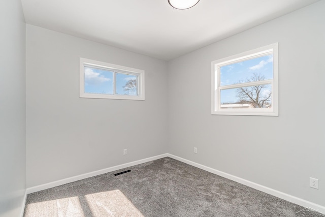 spare room featuring carpet, visible vents, and baseboards