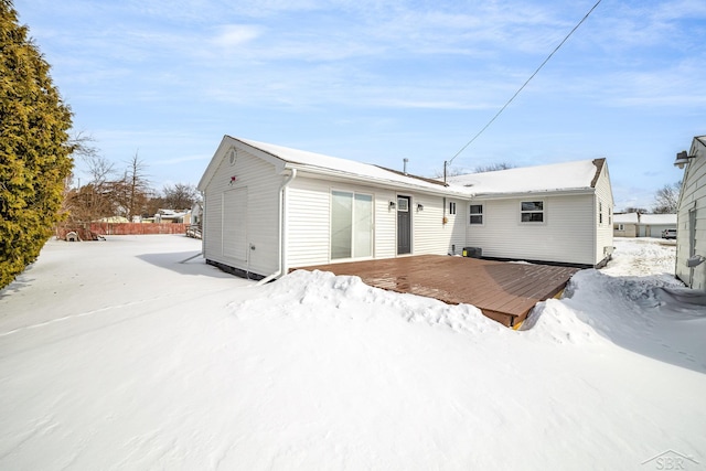 snow covered back of property with a deck