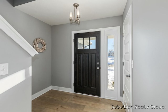 entrance foyer featuring light wood-style flooring, baseboards, and a notable chandelier