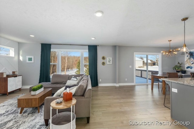 living room with a notable chandelier, recessed lighting, a textured ceiling, light wood-type flooring, and baseboards