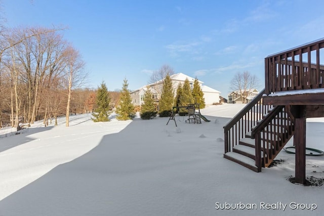 yard layered in snow featuring stairs and a wooden deck