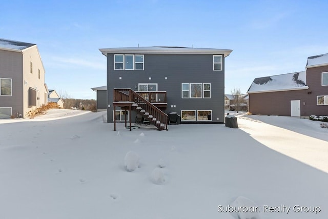 snow covered back of property featuring stairway and a wooden deck