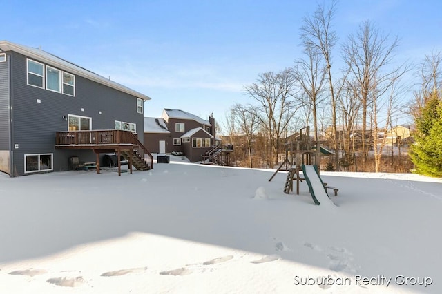 yard covered in snow with stairs, a deck, and a playground