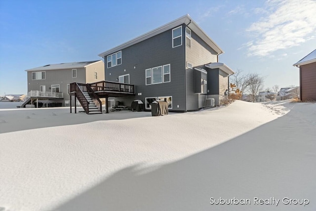 snow covered house featuring stairway, a wooden deck, and central air condition unit