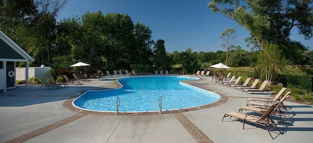 pool with a patio and fence