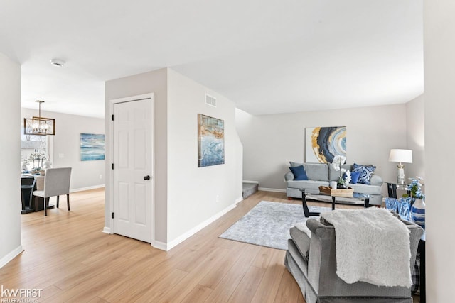 living area with light wood-style floors, baseboards, visible vents, and a chandelier