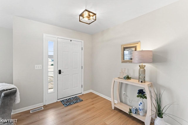 foyer entrance featuring baseboards, visible vents, and light wood-style floors