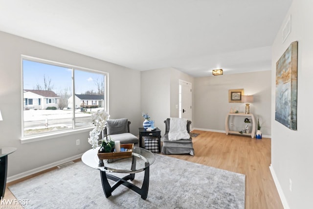 sitting room with visible vents, light wood-style flooring, and baseboards