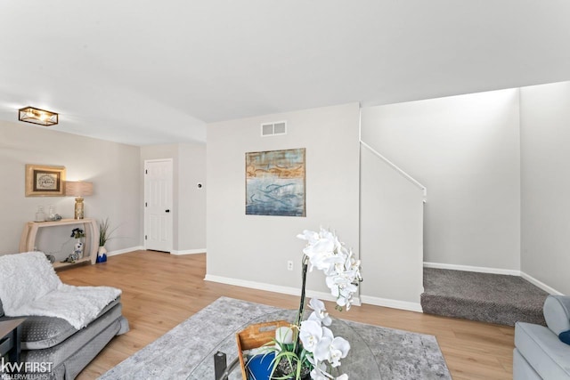 living area featuring light wood-style flooring, visible vents, and baseboards