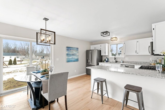 kitchen with a peninsula, appliances with stainless steel finishes, a sink, and light stone counters