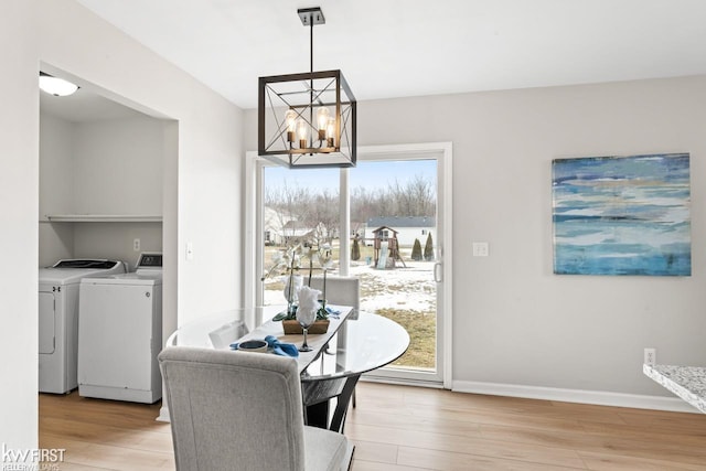 dining space featuring a notable chandelier, light wood finished floors, washing machine and dryer, and baseboards