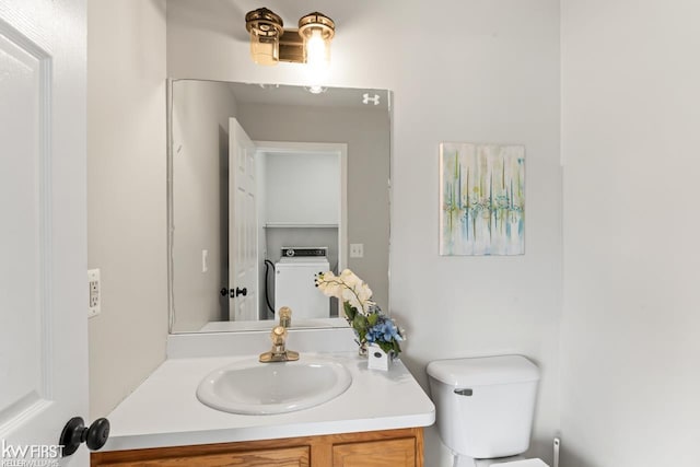 half bathroom featuring washer / clothes dryer, vanity, and toilet