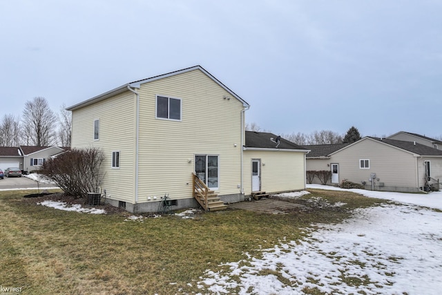 snow covered property with entry steps, a lawn, and central AC