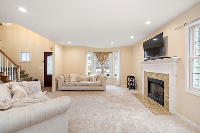 carpeted living area featuring stairs, baseboards, a fireplace, and recessed lighting