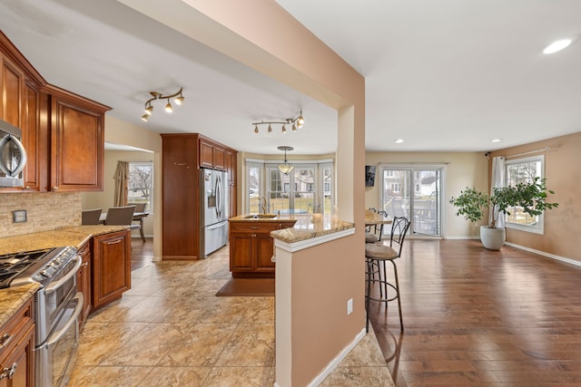 kitchen featuring tasteful backsplash, appliances with stainless steel finishes, a breakfast bar, and light stone counters